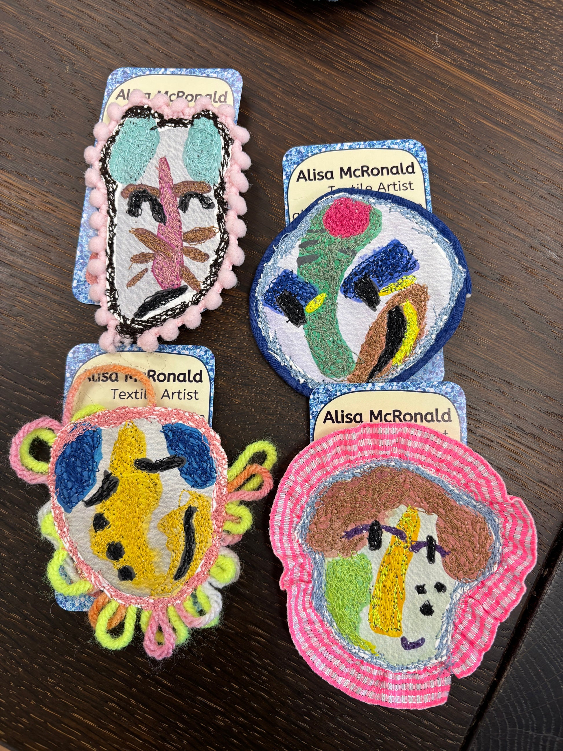 Colorful embroidered patches by Alisa McDonald on a wooden surface